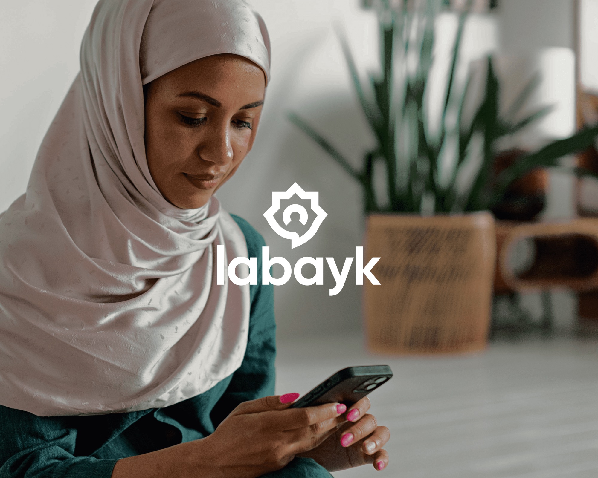Labayk App — a woman holding a phone showing the labayk logo